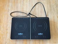 Top-down view of Salton double induction cooktop showing entire unit with power cord on wooden floor.