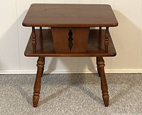 Front view of one maple two-tier end table with turned spun legs and carved central panel