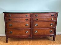 Front view of vintage 8 drawer mahogany dresser with glass top and brass pulls, showing wood grain and drawer arrangement.