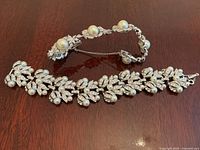 Two vintage rhinestone and pearl bracelets laid out on a table, showing full length and design