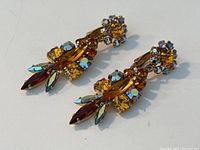 Top view showing front of earrings with topaz and turquoise rhinestones in gold-tone setting.