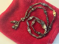 Close-up of the front detail of the vintage silver marcasite necklace showing the floral motif and hanging pendant detail on a red cloth background.