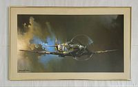 Framed poster showing a signed Spitfire aircraft image with clouds in background, matted in cream and gold brushed metal frame.
