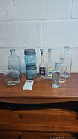Photo showing a variety of vintage glass bottles and two blue-green Ball mason jars stacked