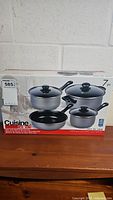 Box showing front image of 7-piece cookware set including pots and frying pan with lids.