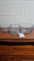 Front view of 4 clear glass Anchor bowls showing 2 small, 1 medium, and 1 large bowls placed on a wooden surface.
