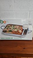 Boxed Basic Essentials 2-piece stainless steel lasagna set showing lasagna pan filled with cooked lasagna.