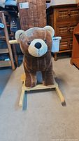 Front view of the child's rocking bear plush toy showing the bear's face and wooden rocker base.