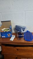 Full view of opened box and all included parts: slicer, inserts, container parts, and stand on wooden surface.