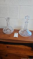 Two Waterford Lismore decanters on a wooden surface, showing their shape and pattern.