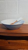 Gray 12-inch ceramic salad bowl with a smooth finish placed on a wooden surface.