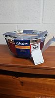 Photo of unopened set of three Oster stainless steel mixing bowls with retail label and maxsold tag