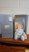 Photo of Precious Moments Missy doll seated in original box, showing full doll and packaging.
