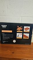 Back of unopened box showing Sharper Image nonstick roasting pan and included tools