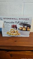 Box front showing product name, image of appliance with pancake puffs, and brand name.