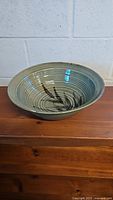 Side angled view of 12-inch pottery bowl showing interior brushstroke design and spiral pattern.
