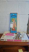 Photo showing unopened Trixie Belden paper doll box resting on top of the Holly Hobbie game box.
