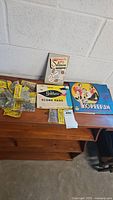 Overview of vintage glass marbles in original packaging along with classic games: 150 Ways to Solitaire, Yahtzee score pads, and Koperecim