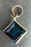 Close-up front view of square-cut blue topaz pendant set in 10K yellow gold.