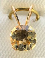 Close-up photo of the 10K yellow gold pendant showing the round faceted citrine gemstone held by four prongs.