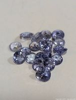 Multiple loose tanzanite gemstones arranged on a neutral surface, showing facets and color.