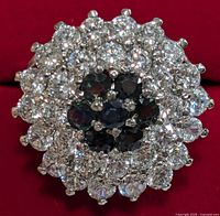 Top view showing oval floral cluster of 7 blue sapphires surrounded by two rows of clear cubic zirconia stones.