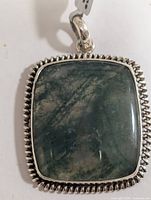 Front view of the rectangular moss agate pendant in silver setting showing stone inclusions and bezel detail.