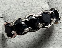 Top close-up of silver ring showing five dark sapphire stones set in a row and secured with prongs.