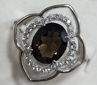 Top view showing oval smokey quartz with halo of clear stones in floral-inspired sterling silver setting.