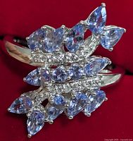 Close-up of the front top view of the silver ring showing the pear-shaped tanzanite stones and small clear accent stones arranged in ornate overlapping design.