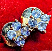 Close-up photo showing pair of silver stud earrings with multiple blue round tanzanite stones in prong settings.