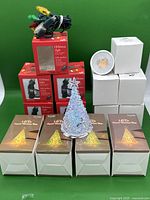 Full lot showing boxed Christmas lights, crystal LED Christmas trees, stacked white boxes with bulbs, and a bundle of chargers on top