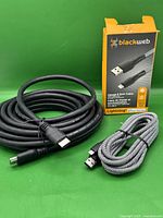 Photo showing both cables coiled: the thick black 25ft HDMI cable and the braided 10ft Blackweb Lightning cable with box.
