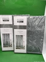 Photo of two Famous Home Etched Rose shower curtains in original packaging showing label and part of each curtain.