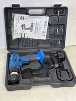Open black plastic carrying case containing blue Bolton cordless drill without battery, black charger with power cord, five drill bits in molded slots, and a printed manual.