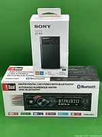 Photo of both items with their retail boxes: Sony ICF-P27 AM/FM radio box and Dual XRMS9BT Bluetooth car stereo box, set against a green background.