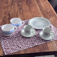 Photo shows 2 Palluy France vintage soup bowls with blue checkered and floral design, 2 Royal Doulton Shadow Play cups with matching saucers, and 1 Royal Doulton plate laid out on a magenta patterned cloth on a wooden surface.