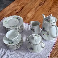 Full set view of plates, saucers, teacup, sugar bowl, creamer, and teapot showing collection and pattern.