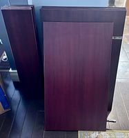 Photo of a stack of several cherry laminate cabinet doors, showing a dark reddish-brown smooth flat panel design with visible edges, no hardware.
