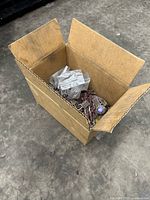 Open cardboard box containing a variety of Dremel sanding attachments.