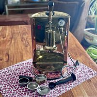 Front view of entire espresso machine with detached portafilter handle and filter baskets arranged in front