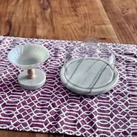 Marble footed cheeseboard and marble and milk glass pedestal dish on patterned cloth