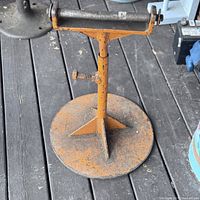 Front view of the antique metal roller stand showing round base and adjustable horizontal roller.