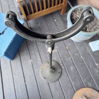 Close-up front view of the metal stand’s curved top holder and round base, showing wear and connection points.