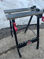 Side angle view of Jobmate portable work table showing clamping bars and red adjustment handles.