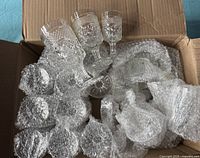 Top-down view of a cardboard box with a mixture of bubble wrap and multiple Wexford glass goblets of varying sizes packed inside.