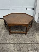 Full front view of hexagonal oak cocktail table showing barley twist legs and raised edge