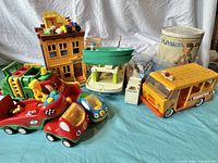 Wide view showing assortment of vintage Fisher-Price, Playskool, Buddy L toys including cars, boat, school bus, and bucket of blocks.