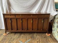 Front view of walnut-stained 12-drawer dresser showing four top drawers and six recessed-panel doors with ring-pull hardware.