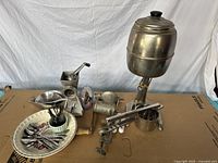 Photo of the full lot showing antique cream dispenser, vintage grinders, metal ricer, cutlery, serving tray and utensils.